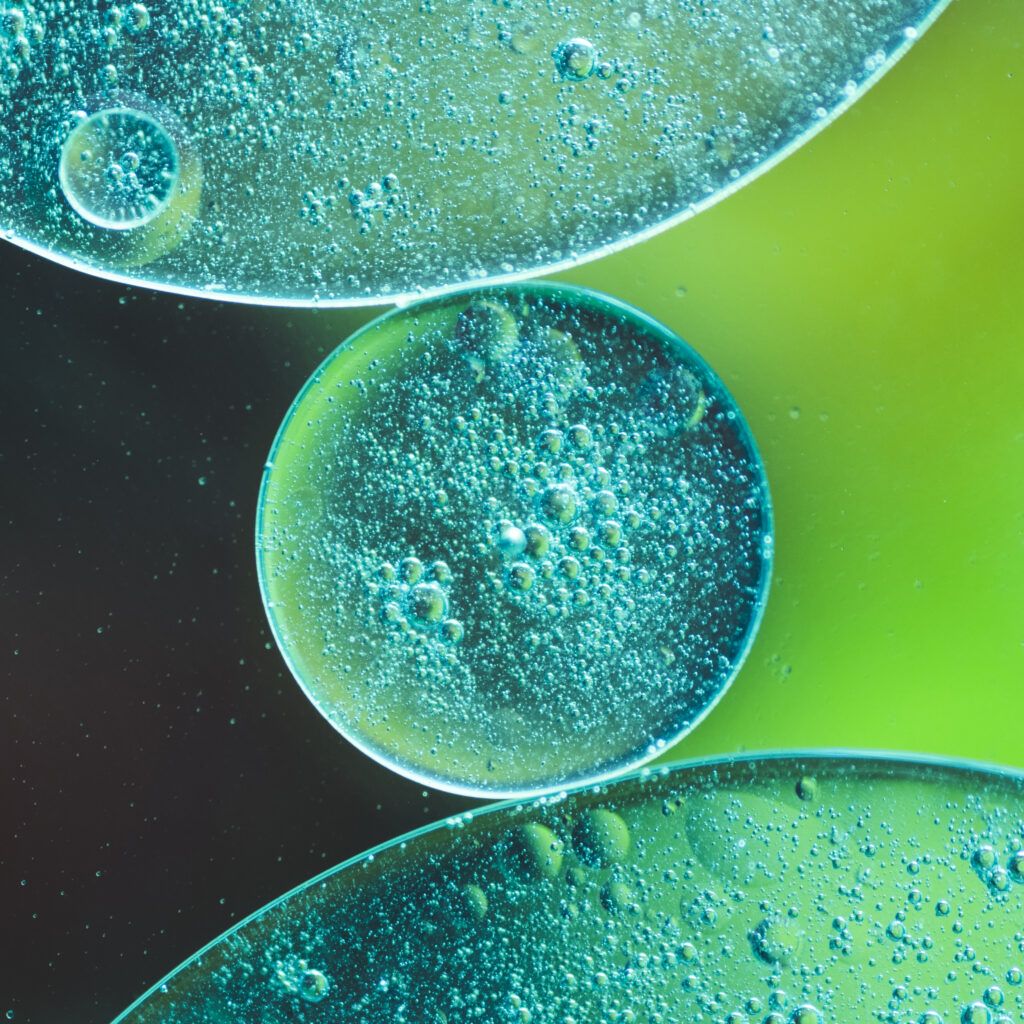 gotas de aceite translucido en liquido sobre fondo borroso colorido